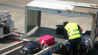 Bari, İtalya-24 Eylül 2018: Havaalanı personeli bavulları bir uçağın içine yüklüyor. Taşıyıcı bant uçağının bagajı. Kalkış terminalinde yolcu bavullarını düzenleyen bir işçi.