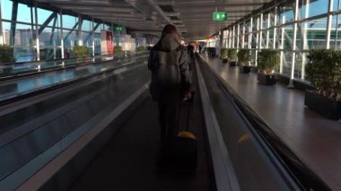 Amsterdam, Hollanda-05 Aralık 2016: Amsterdam Schiphol Uluslararası Havalimanı 'nda manyetik merdivenlerdeki yolcuların 4K takibi. Modern terminal lobisinde yürüyen insanlar. Dan kapısı.