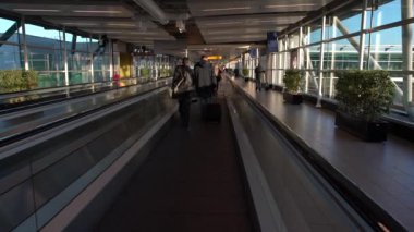 Amsterdam, Hollanda-05 Aralık 2016: Amsterdam Schiphol Uluslararası Havalimanı 'nda manyetik merdivenlerdeki yolcuların 4K takibi. Modern terminal lobisinde yürüyen insanlar. Dan kapısı.