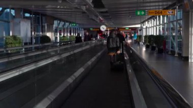 Amsterdam, Hollanda-05 Aralık 2016: Amsterdam Schiphol Uluslararası Havalimanı 'nda manyetik merdivenlerdeki yolcuların 4K takibi. Modern terminal lobisinde yürüyen insanlar. Dan kapısı.