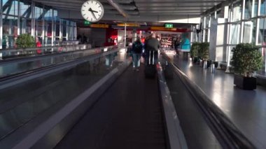 Amsterdam, Hollanda-05 Aralık 2016: Amsterdam Schiphol Uluslararası Havalimanı 'nda manyetik merdivenlerdeki yolcuların 4K takibi. Modern terminal lobisinde yürüyen insanlar. Dan kapısı.