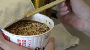 4K Asyalı kadın yolcu hazır erişte yiyor ve uçuş sırasında uçağın içinde çay içiyor.