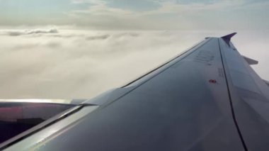 4K, kalkış sırasında beyaz bulutların arasında uçan uçak kanadı kabinindeki gezgin görüntüsü. Yukarıdan gelen güzel bulutlar güzel mavi gökyüzü ve güneşli bir yolculukta. Hava yoluyla seyahat. -Dan.