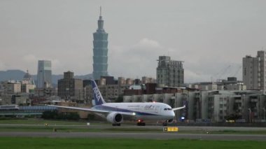 Taipei, Tayvan-10 Kasım 2018: Ticari yolcu uçaklarının Yavaş Hareketi arka plandaki Taipei 101 Kulesi 'nin görüntüsüyle havalanır. Songshan havaalanındaki uçak. Akşam uçuşu - Dan