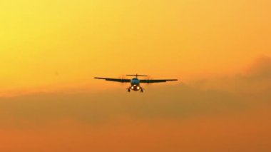 Gün batımında yavaş çekim uçuşu. Bir Ticari Yolcu Uçağı Tepenin Üzerinde Uçuyor. Jet uçağı ya iniş yapacak ya da ulusal havaalanına park edecek. 120 fps-Dan hızında ağır çekim.