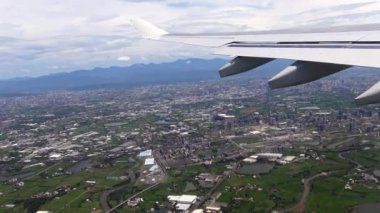 4K hava yoluyla seyahat ediyor. Tayvan Adası 'ndaki bir şehrin havadan görünüşü, Uçuş-Dan sırasında bir uçak penceresinden görüldüğü gibi arka plandaki uçağın ve dağın kanadını görün.