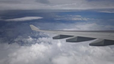 4K hava yoluyla seyahat ediyor. Gökyüzünde bir sürü bulutla gökyüzü manzarası ve yukarıdan okyanus, bir uçak penceresinden görülebildiği gibi - Dan