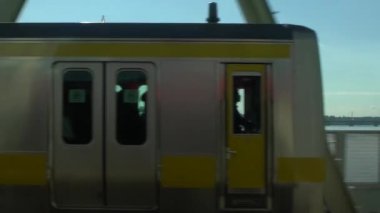 Ağır çekim tren Tokyo, Japonya 'daki nehir köprüsünden geçiyor. Tren bir tren istasyonundan kalkıyor. Köprü Dan 'i geçiyor.