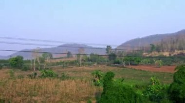 Eski demiryolundaki hareket halindeki lokomotiften orman ve dağın 4K görüntüsü. Tayland 'da seyahat eden bir yolcu treni. Manzara Geçiyor - Dan