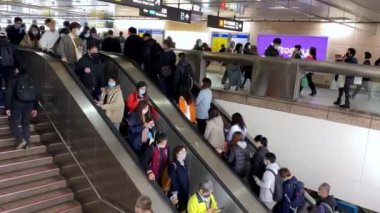 Taipei, Tayvan-06 Şubat 2020: 4K, metro girişindeki yürüyen merdivenlerde bulaşıcı hastalıklara karşı koruyucu maske takan Asyalı insanlar tren istasyonuna gidiyor. Coronavirus koruması - Dan