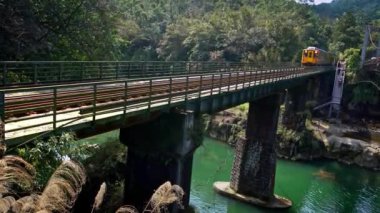 4K Nehir üzerindeki köprüden geçen sarı bir trenin güzel manzarası, gündüz Shifen köyünden geçen. İnsanlar Tayvan-Dan 'deki Çin festivali gökyüzü fenerlerine gidiyor
