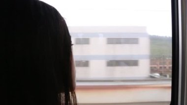 Trende oturan ve pencereden dışarı bakan üzgün genç bir kadının yakın plan fotoğrafı.