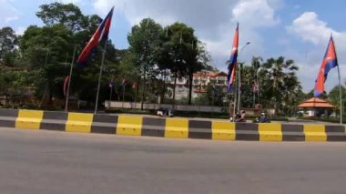 Siem Reap, Kamboçya-20 Nisan 2018: 4k, Güney Doğu Asya 'da bir caddeyi takip eden tuk tuk tuk içinde bir turistin POV' u. Paralel görüş açısı ve bulutları olan asfalt bir yolda yerel bir taksi yolculuğu kaydediyorum.