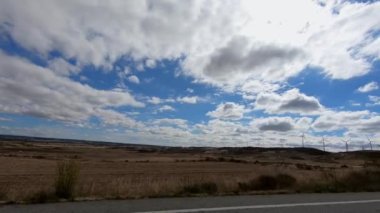 4K, İspanya 'nın yel değirmenleriyle güzel kırsallarda araba sürüyor. Mavi gökyüzüyle aydınlık bir yaz gününde yola çıkmak. Alanın İspanyol manzarası. -Dan.