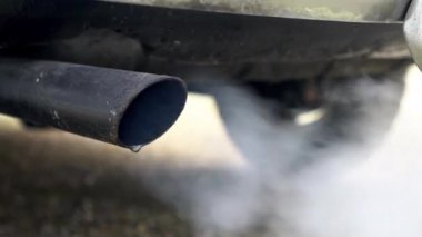 Arabanın egzoz borusundan çıkan yakın çekim dumanı beyaz dumana neden oluyor. Yoldaki araçtan zehirli karbon monoksit, hava kirliliği konsepti. Trafikte duman emisyonları