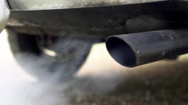 Arabanın egzoz borusundan çıkan ve beyaz dumandan çıkan yavaş yanma dumanı hareketi. Yoldaki araçtan zehirli karbon monoksit, hava kirliliği konsepti. Trafikte duman emisyonları