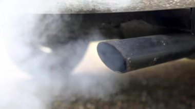 Arabanın egzoz borusundan çıkan ve beyaz dumandan çıkan yavaş yanma dumanı hareketi. Yoldaki araçtan zehirli karbon monoksit, hava kirliliği konsepti. Trafikte duman emisyonları