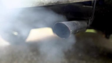 4K, araba egzoz borusundan çıkan yakın çekim dumanı çok güçlü beyaz dumandan. Yoldaki araçtan zehirli karbon monoksit, hava kirliliği konsepti. Trafikte duman emisyonları