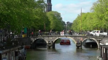 Amsterdam, Hollanda-13 Mayıs 2019: Amsterdam Kanalı 'ndaki köprüden ağır tekne geçişi. Ünlü Hollanda kanalları ve eski Avrupa şehri. Seyahat konsepti arka planda.