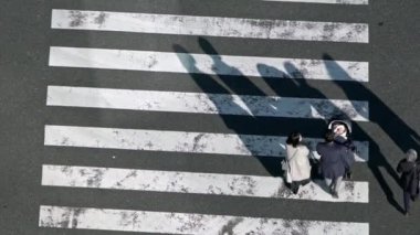 Tokyo, Japonya-02 Şubat 2020: ağır çekimde trafik arabaları ve gün batımında yaya geçidi kalabalığı. En yoğun yol kavşağında yürüyen Asyalıların manzarası yükseldi.