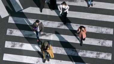 Tokyo, Japonya-02 Şubat 2020: Gün batımının ışığıyla kavşakta kalabalık yaya geçidi üzerinde yavaş çekim. Asyalıların yoğun yaya geçidi görüntüsü. - Dan.
