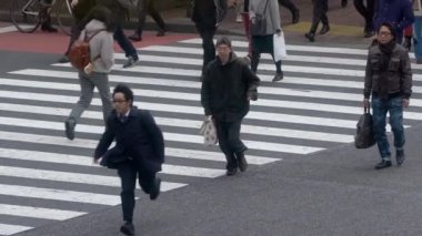 Tokyo, Japonya-04 Şubat 2020 Shibuya kavşağındaki kalabalık yaya geçidinde ağır çekim. Asyalıların kalabalık yaya geçidinde hava görüntüsü. Gün ortasında Asya 'da. Metropolitan Şehir-Dan