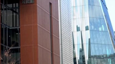 Tokyo, Japonya-03 Şubat 2020: Yüksek binadaki camları temizleyen bir bakım işçisinin yavaş hareketi. Cam cephede cam temizleyicisi çalışıyor. Riskli taşıyıcı ayna temizleme kulesi.