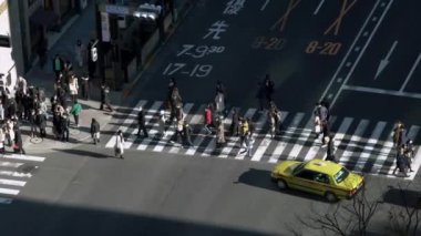 Tokyo, Japonya-02 Şubat 2020: 4K, gün batımının ışığıyla kavşakta kalabalık bir yaya geçidinde görüntüyü yükseltti. Asyalıların yoğun yaya geçidi görüntüsü. - Dan.