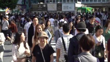 Tokyo, Japonya-29 Eylül 2017: 4K Shibuya kavşağından geçen kalabalık yayaları taşıyor. Dolly yerel Asyalıları vurdu ve turistler en işlek yol kavşağında yürüyorlar.
