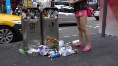 Taipei, Tayvan-13 Ağustos 2017: 4K. Taipei caddesindeki aşırı dolu çöp tenekesinden dökülen çöp. Asyalı bir kadın yolda yürürken çöp kutusuna çöp atıyor. Şişeler, teneke kutular ve diğer çöp kutuları - Dan