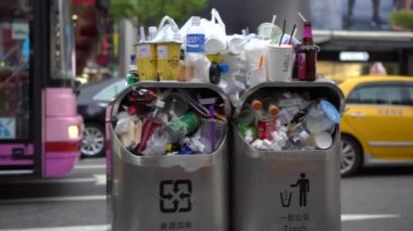 Taipei, Tayvan-13 Ağustos 2017: 4K. Taipei caddesindeki aşırı dolu çöp tenekesinden dökülen çöp. Asyalı bir kadın yolda yürürken çöp kutusuna çöp atıyor. Şişeler, teneke kutular ve diğer çöp kutuları - Dan