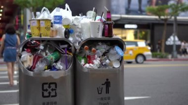 Taipei, Tayvan-13 Ağustos 2017: 4K. Taipei caddesindeki aşırı dolu çöp tenekesinden dökülen çöp. Asyalı bir kadın yolda yürürken çöp kutusuna çöp atıyor. Şişeler, teneke kutular ve diğer çöp kutuları - Dan