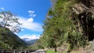 4K, dağ yolunda Taitung 'da virajlarla ormanın içinden geçiyor. Işıl ışıl bir Tayvan günüyle boş bir yolda araba sürmek. Asya dağlarında kayalıkların olduğu bir manzara. Dan otoyolunda seyahat.