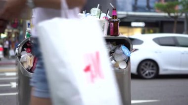 Taipei, Tayvan-13 Ağustos 2017: 4K. Taipei caddesindeki aşırı dolu çöp tenekesinden dökülen çöp. Asyalı bir kadın yolda yürürken çöp kutusuna çöp atıyor. Şişeler, teneke kutular ve diğer çöp kutuları - Dan