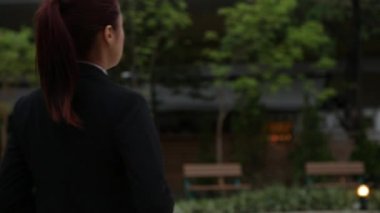 Asyalı iş kadını zor bir günde işini bitirdi ve ceketini çıkardı, akşamleyin dinlenmek için Taipei 'deki parka doğru yürüyordu.