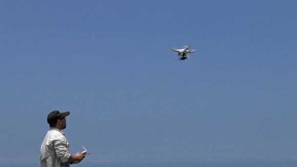 Professionalの男性はリモコン付きドローンをプレイしています 青い空を背景にした現代のRc無人ヘリコプター飛行を制御する男性パイロット 飛行四分儀ダン — ストック動画
