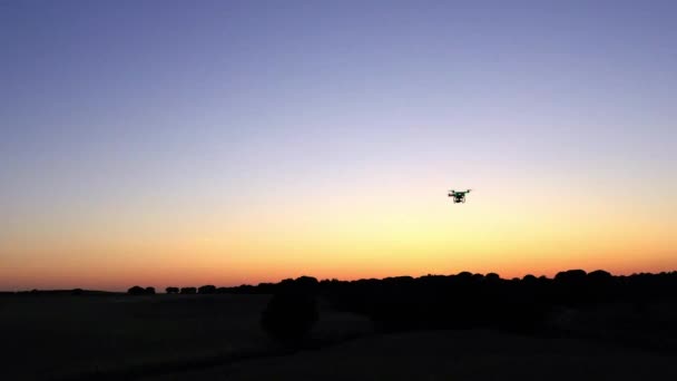 日没の空とフィールド上のデジタルカメラで飛行ドローンクワッドコプターの空中ビュー スペインの田舎の風景 オレンジ色の太陽の下で美しい景色 現代の新技術 — ストック動画