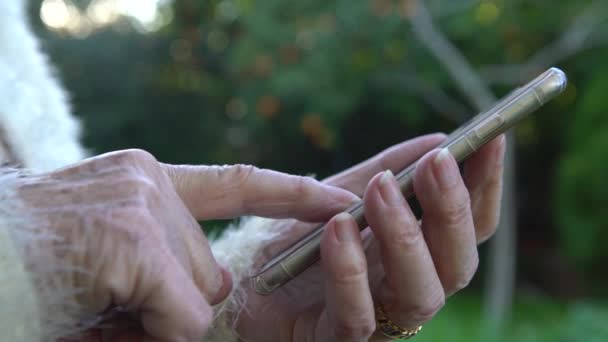 4K Vieilles mains de grand-mère tenant un téléphone portable. Grand-mère en utilisant et en regardant le téléphone intelligent dans la maison de jardin Dan 