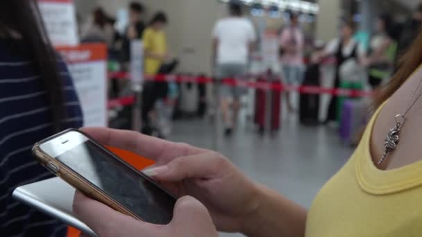 4K亚洲女游客在国际机场等候报到柜台时检查电话 在旅行度假期间 人们用智能手机和朋友们的社交网络快速发短信 — 图库视频影像