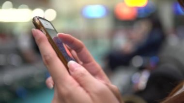 Tayvan havaalanında cep telefonunda yazan 4K Genç Asyalı kadın. Kız akıllı telefonu kontrol et. Bekleme odasında oturan insanlar seyahat etmek için uçağa biniyorlar.