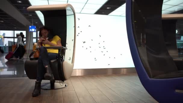 年轻的亚洲女人在国际机场用手机打字 女孩检查智能手机和上网 人们坐在候机室等着坐飞机去旅行 — 图库视频影像