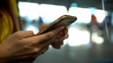4K, uluslararası havaalanında kaldırımda cep telefonu yazan Asyalı genç bir kadın. Kız akıllı telefonu kontrol et. Seyahat terminalinde seyahat eden insanlar uçağa biner.