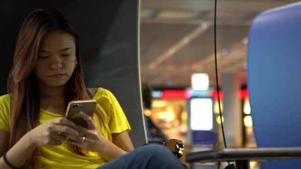 4K, Jeune femme asiatique tapant sur téléphone portable à l'aéroport international. Fille vérifier le smartphone et surfer sur Internet. Les voyageurs assis dans la salle d'attente pour prendre l'avion pour voyager-Dan 