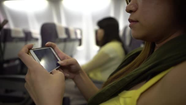 4K亚洲妇女内陆飞机 飞机上的乘客在飞行过程中使用装置电话 查一下智能手机 — 图库视频影像