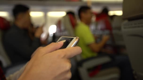 2018年4月20日 飛行機内に携帯電話を持つ4Kの若い女性 飛行機の中でスマートフォンを使っているアジアの女の子 フライト中にデバイス電話を使用している乗客 旅行者チェック スマートフォン Dan — ストック動画