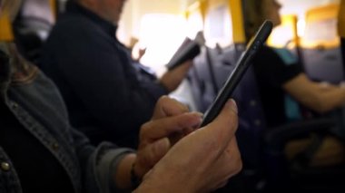 4K, uçağın içinde cep telefonu olan beyaz bir kadın. Uçakta akıllı telefonu tutan bir kadın el. Uçuş sırasında cihaz telefonu kullanan bir yolcu. İnsanlar akıllı telefonları kontrol eder.