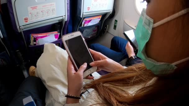 亚洲女人在飞行途中拿着智能手机 旅行者在飞机上坐下来 用电话装置看到飞机上的信息 — 图库视频影像