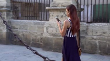 4K, Asyalı meşgul kadın Seville caddesinde yürürken akıllı telefondan mesaj atıyor. İspanya 'da cep telefonu sohbeti yapan bir kız. Seyahat sırasında gezginler cihaz telefonu kullanıyor