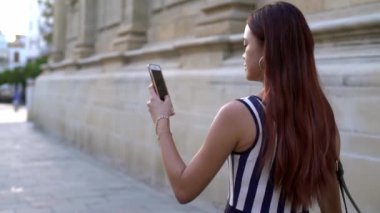 4K, Asyalı meşgul kadın Seville caddesinde yürürken akıllı telefondan mesaj atıyor. İspanya 'da cep telefonu sohbeti yapan bir kız. Seyahat sırasında gezginler cihaz telefonu kullanıyor