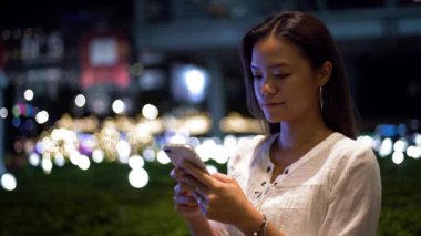 4K, Asyalı kadın gece akıllı telefondan mesaj atıyor. Taipei caddesinde cep telefonu sohbeti yapan bir kız. Seyahat sırasında gezginler cihaz telefonu kullanıyor